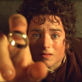 An iconic scene from the Lord of the Rings Film where Frodo Baggins is lying on the ground, reaching upward and the ring is falling onto his finger.