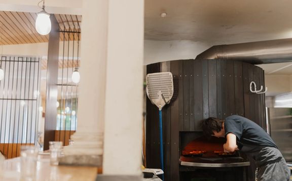 A chef puts a pizza into a woodfire oven at Loretta in Wellington.