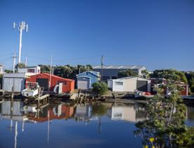 The Petone boat ramp, Hikoikoi,  with colourful boat sheds and boats in the morning sun.