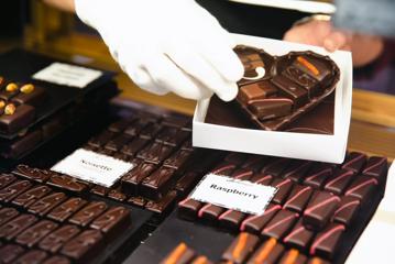 Chocolates being packaged into a heart-shaped chocolate mold, inside a small white box at Bohemein Fresh Chocolates, a chocolate shop.