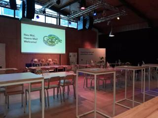 An empty room set up for a conference in Prefab Hall, light wood furniture matches the walls and floor.