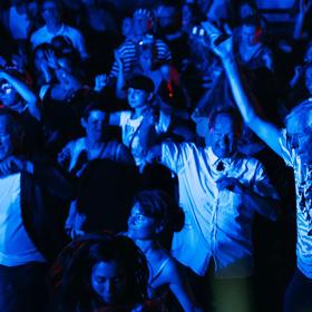 A crowded dancefloor illuminated by blue-coloured lights at the Morning People: Warehouse Rave.