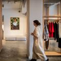 A person in a long striped gown walks through a boutique clothing store.