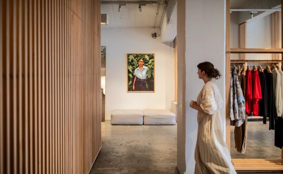 A person in a long striped gown walks through a boutique clothing store.