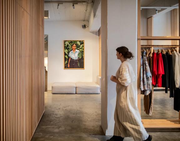 A person in a long striped gown walks through a boutique clothing store.