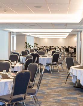 A conference room inside the James Cook Hotel Grand Chancellor located on The Terrace in Wellington Central. The room is setup with many large round tables with eight chairs at each.
