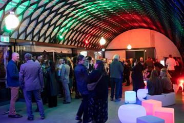 People stand around inside the Kamala function room at Wellington Zoo. There are square boxes that are illuminated and act as seats.