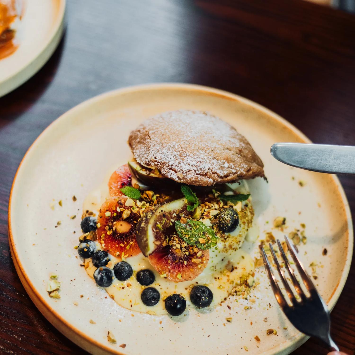 A dessert with blueberries, red kiwi, fig and pastry.