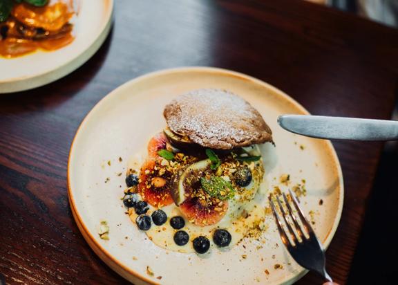 A dessert with blueberries, red kiwi, fig and pastry.