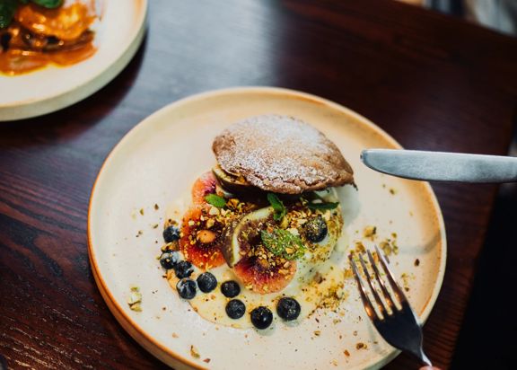A dessert with blueberries, red kiwi, fig and pastry.
