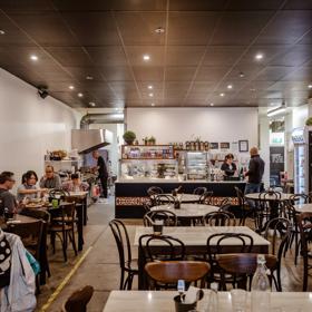 The interior of Little Penang on Victoria Street, customers enjoy their meals and the chef is seen in the kitchen out the back.