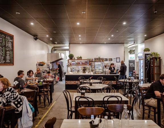 The interior of Little Penang on Victoria Street, customers enjoy their meals and the chef is seen in the kitchen out the back.