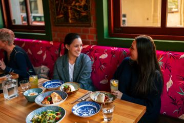 Two people share Vietnamese food and drinks at Apachè.