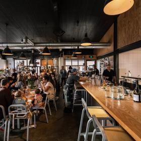 The interior of Prefab Eatery, a restaurant located on Jessie Street and Ebor Street in Te Aro Wellington, is filled with people enjoying food and drinks.