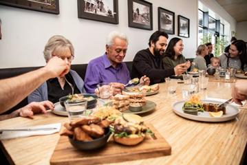 A whānau (family) sat at a table inside Kāinga eatery, enjoying their meals and chatting.