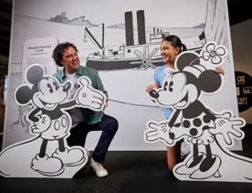 A father and daughter pose with cardboard cut-outs of Mickey and Minnie Mouse on display at the Disney: Magic of Animation exhibition.