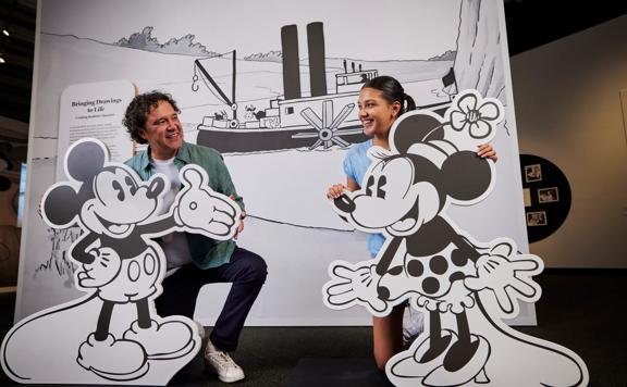 A father and daughter pose with cardboard cut-outs of Mickey and Minnie Mouse on display at the Disney: Magic of Animation exhibition.