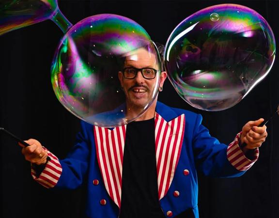 Dr Hubble uses wands to create large bubbles.