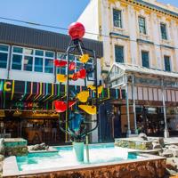 People walking down Cuba Street, past the Bucket Fountain, an iconic kinetic sculpture.