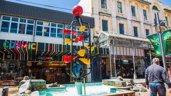 People walking down Cuba Street, past the Bucket Fountain, an iconic kinetic sculpture.