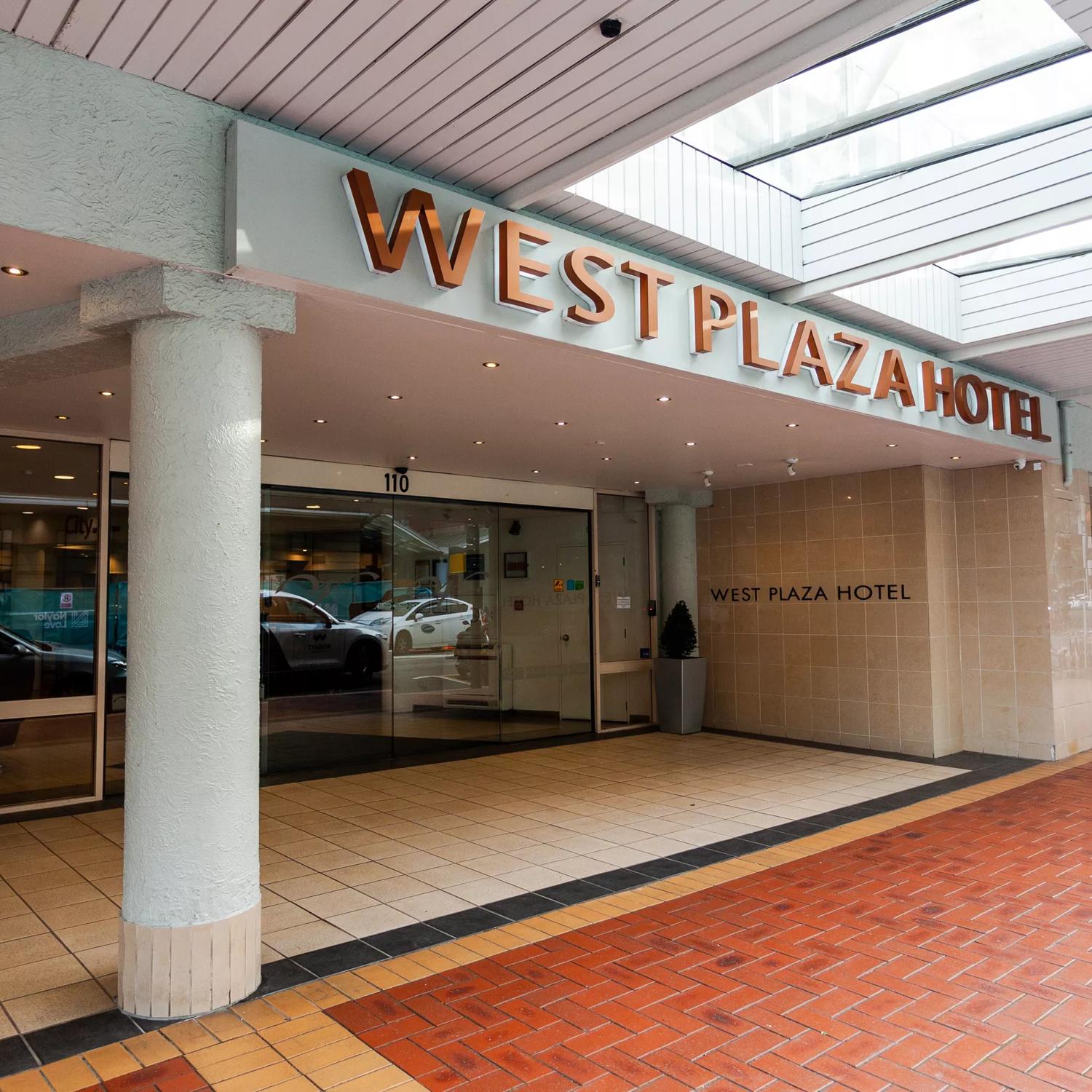The exterior of West Plaza Hotel, with a tiled floor and large sliding doors.