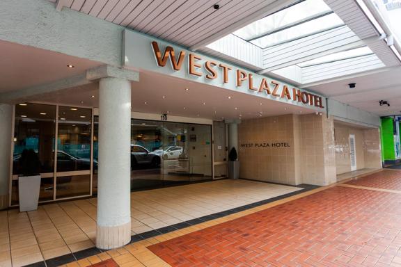 The exterior of West Plaza Hotel, with a tiled floor and large sliding doors.