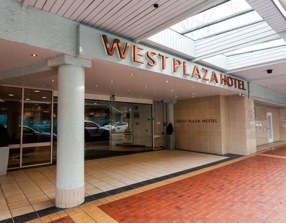 The exterior of West Plaza Hotel, with a tiled floor and large sliding doors.