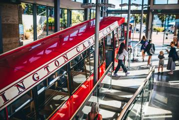 The Wellington Cable Car parked at the top terminal, people walk in and out of the doors.