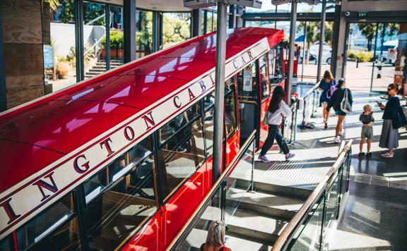 The Wellington Cable Car parked at the top terminal, people walk in and out of the doors.