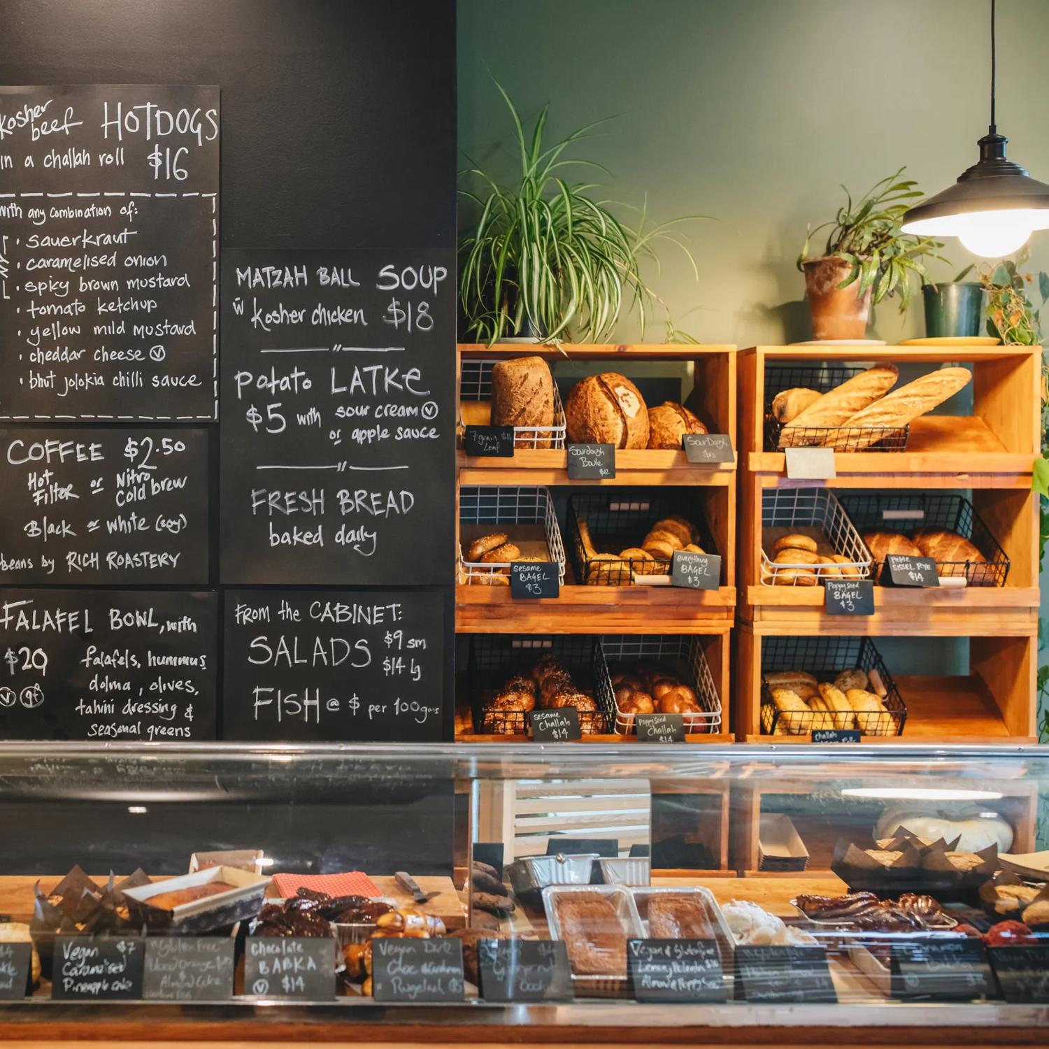 The counter at The Bond Street Deli with plenty of baked goods for sale and a chalkboard menu on the back wall.