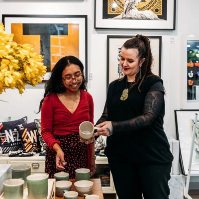 An employee helps a shopper choose a piece of potery to buy at the Te Papa Store.