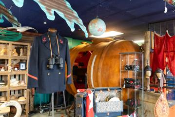 A nautical-themed store where a manican bust wears a navy blue captain's jacket and binoculars.