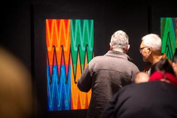 Two people looking at an abstract painting in a museum.