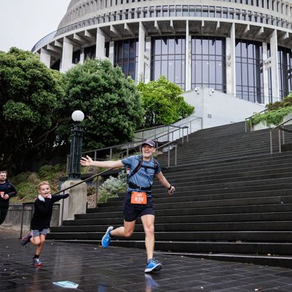 A Faultline Ultra participant, and a few supporters, are running by the New Zealand Parliament building.