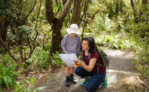 Mother and child looking at paper map on the Te Ara Koukouoro trail at Ōtari-Wiltons Bush.