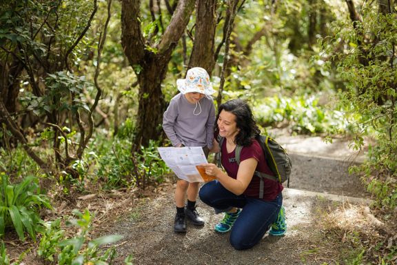 Mother and child looking at paper map on the Te Ara Koukouoro trail at Ōtari-Wiltons Bush.