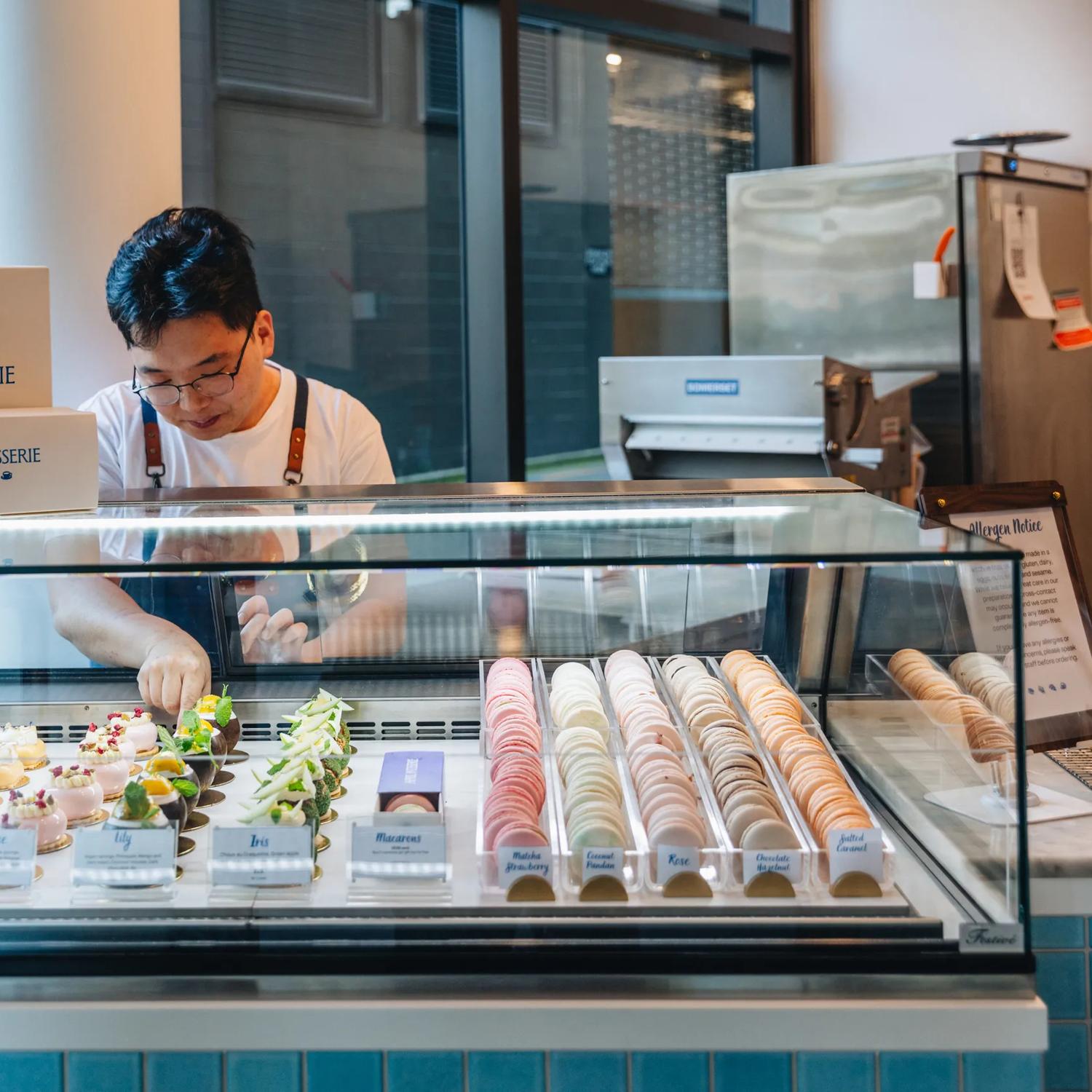 A staff member arranges desserts in the display case at April Patisserie.