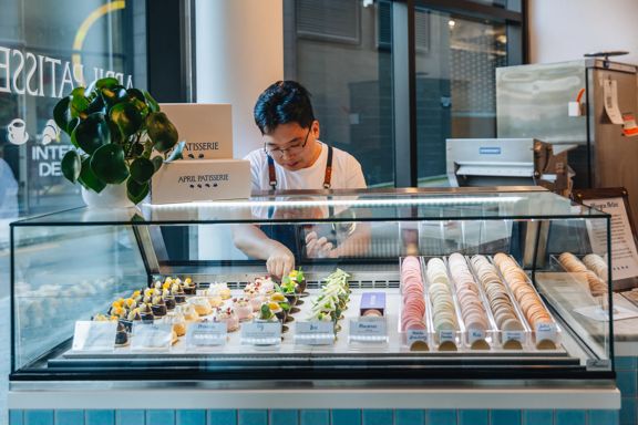 A staff member arranges desserts in the display case at April Patisserie.