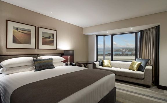 Room inside intercontinental Wellington overlooking Oriental Paradeh a doouble bed and couch by the window.