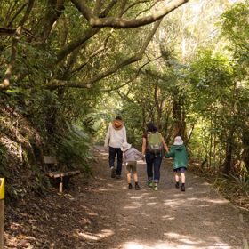 Two adults and two kids walking on a trail at Ōtari-Wilton's Bush