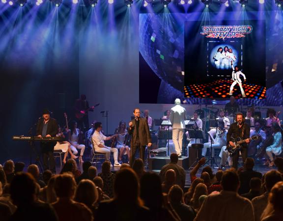 The Best of the Bee Gees Saturday Night Fever and the George Ellis Orchestra perform on stage with blue spotlights.