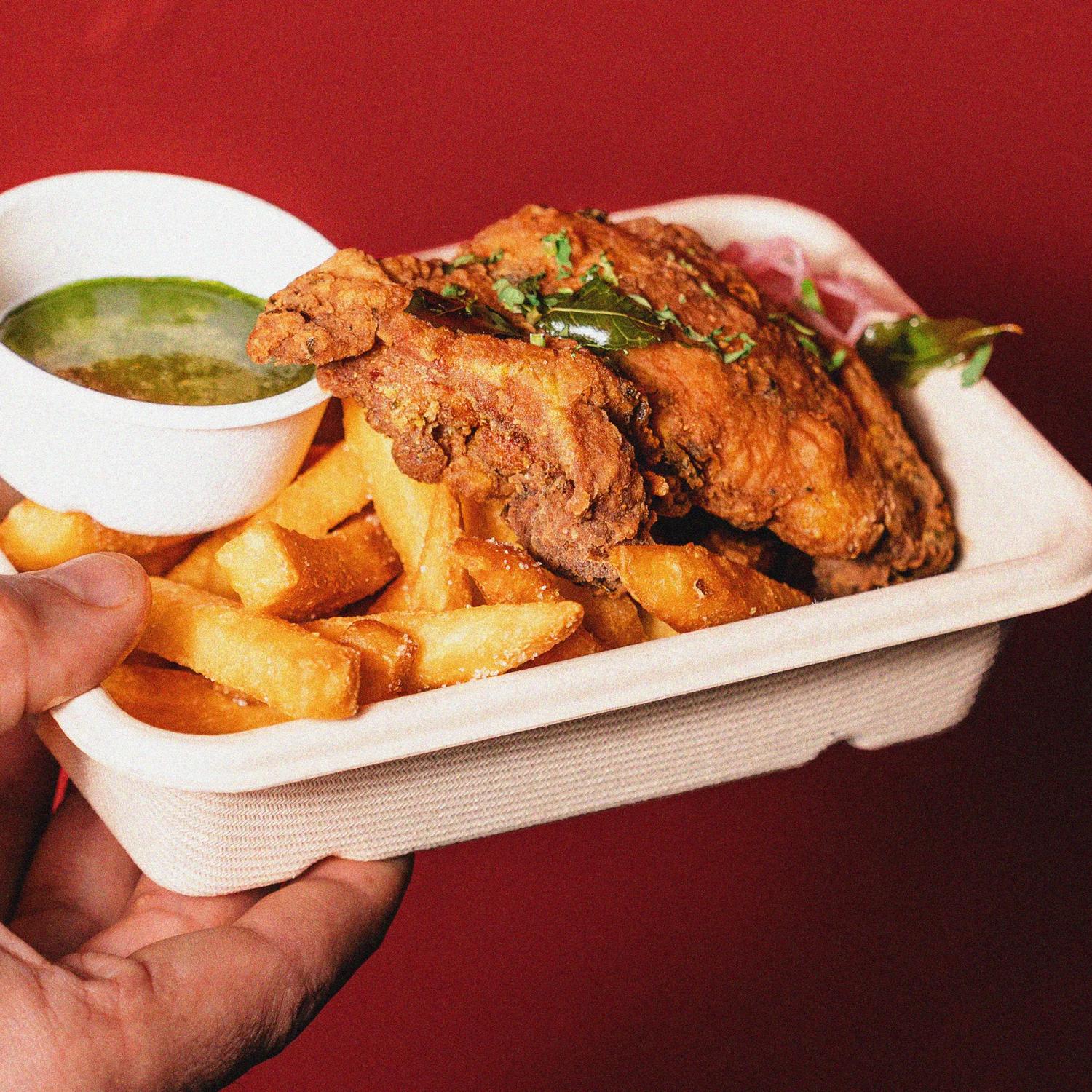 A curry leaf fried chicken with chips from Flutter Chicken Co. in a takeaway container.