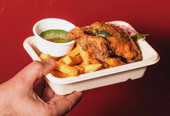 A curry leaf fried chicken with chips from Flutter Chicken Co. in a takeaway container.