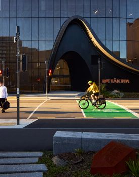 A pedestrian crosses the road outside Tākina, while a cyclist waits in the cycle box.