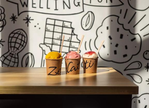 3 tubs of ice cream and sorbet on a table inside Zelati Dessert Cafe.