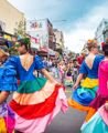 Dancers in colourful outfits twirling around the CupaDupa street festival.
