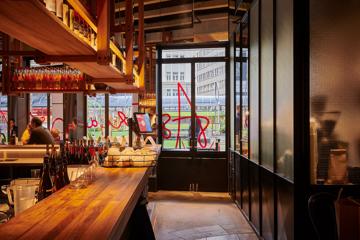 Interior of Astoria looking out the windows onto street with customers dining in background.