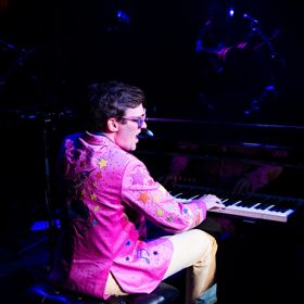 Sir El Tom in a pink jacket playing the keyboard