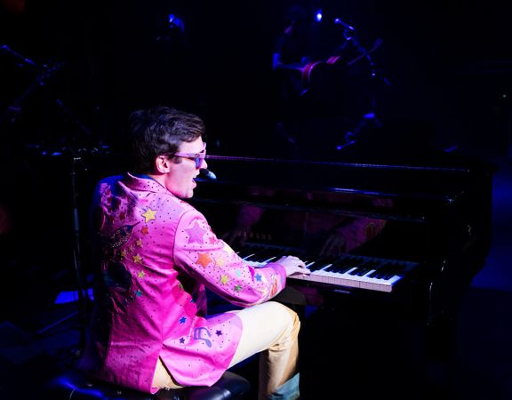 Sir El Tom in a pink jacket playing the keyboard