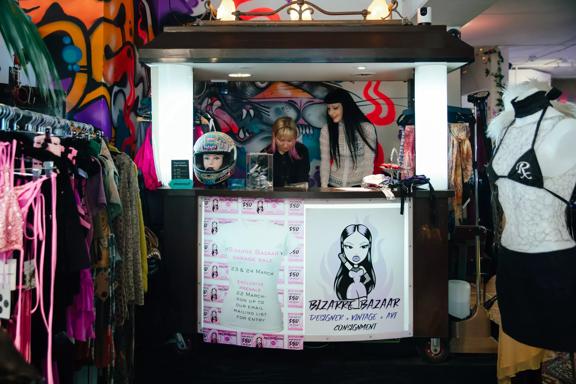 Two employees are behind the counter at Bizarre Bazaar, a secondhand clothing store in Wellington.